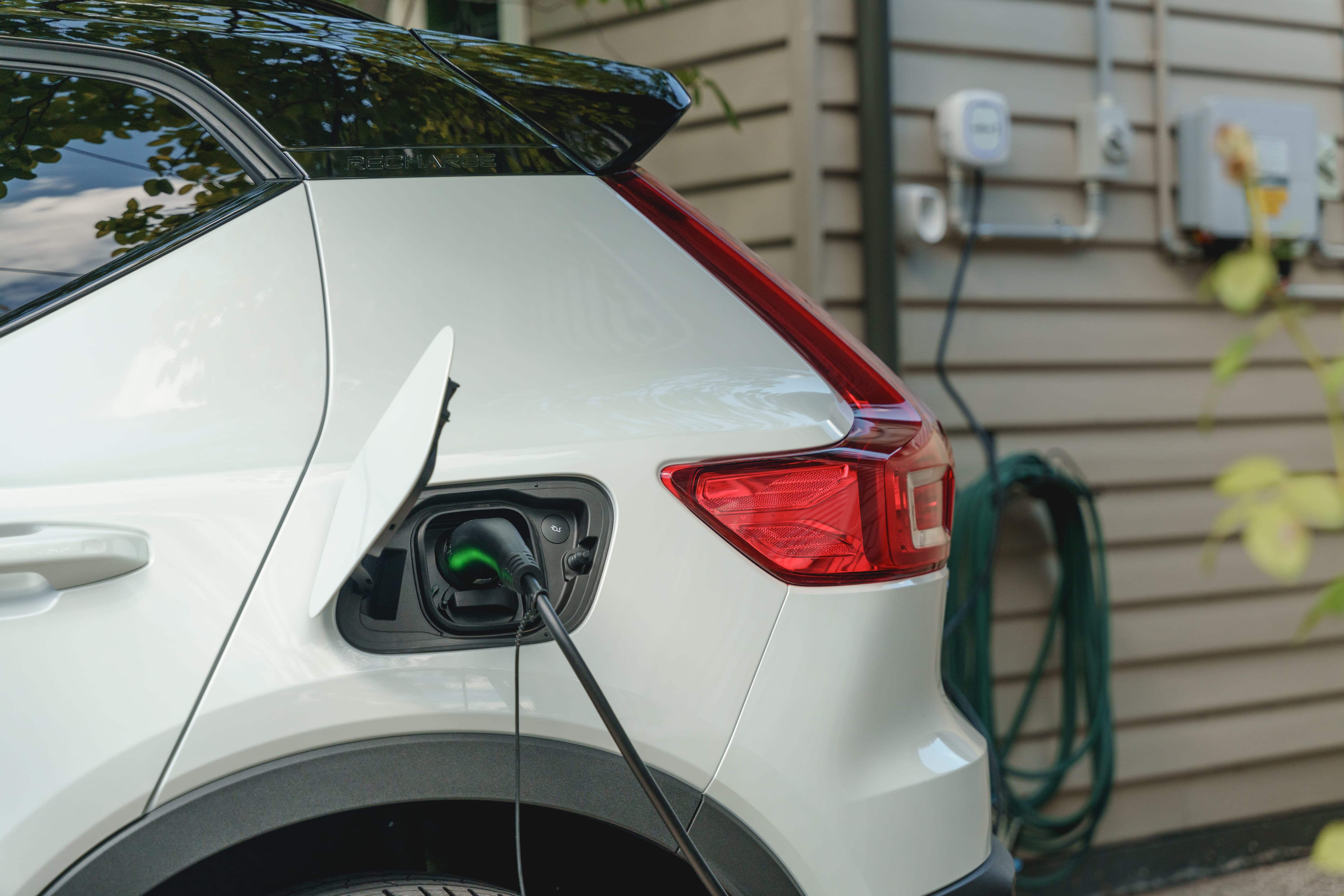 An electric car standing stationary in the driveway while it charges.